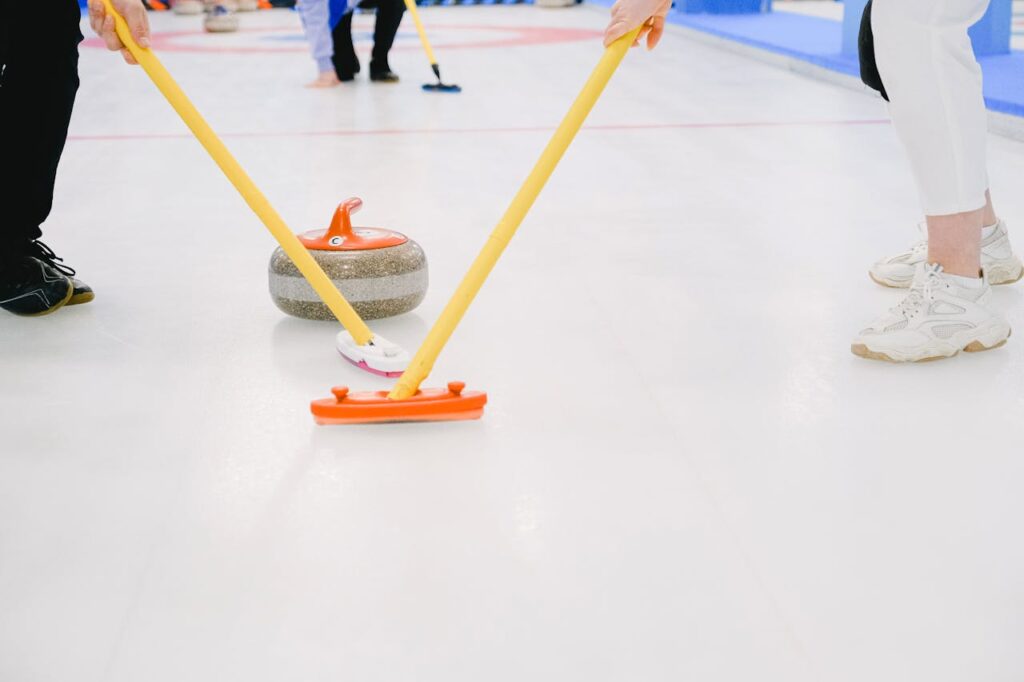 Atletas de curling varrendo na frente da pedra.