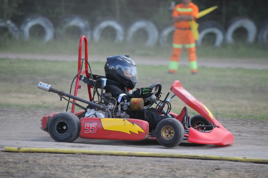 Piloto dirigindo um kart vermelho e amarelo.